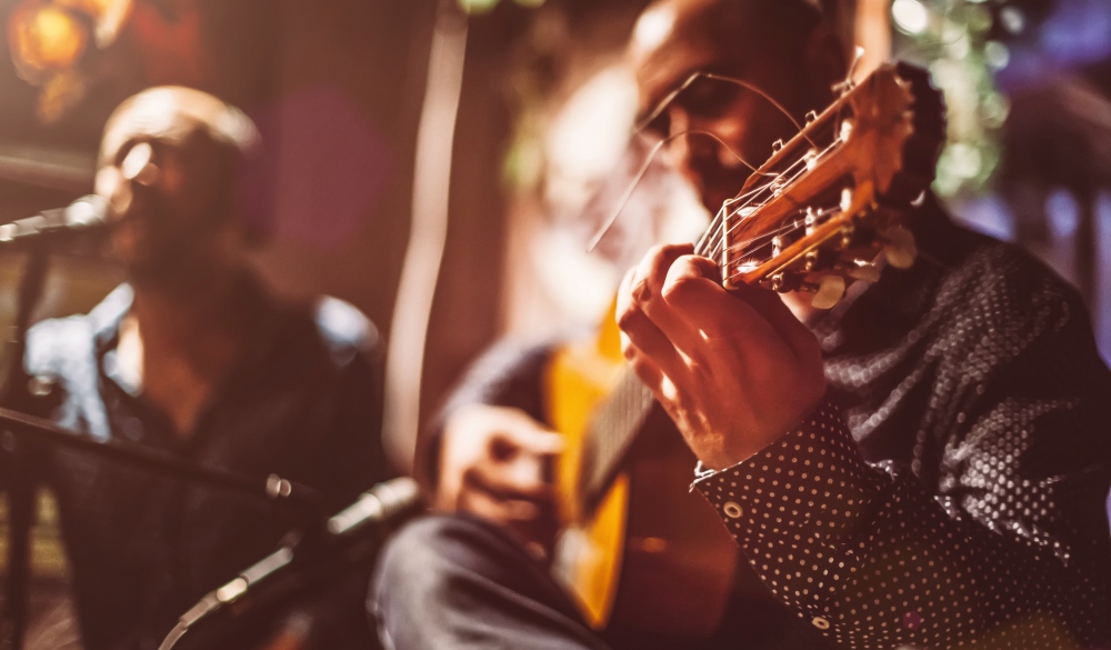 Two male musicians on a stage performing traditional flamenco music.