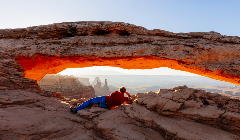 Man enjoying sunrise at Mesa arch, Canyonland