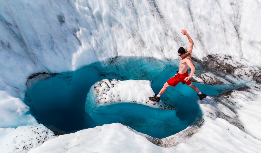 A man jumps onto an island of ice on Root Glacier in Wrangell-St. Elias National Park
