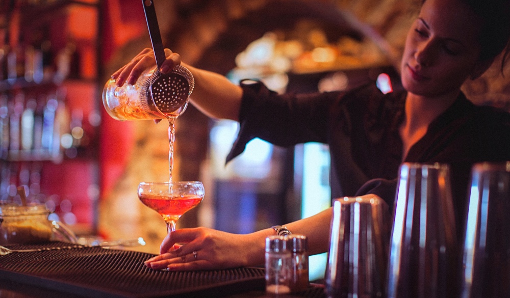 female bartender pouring cocktails in a cocktail bar